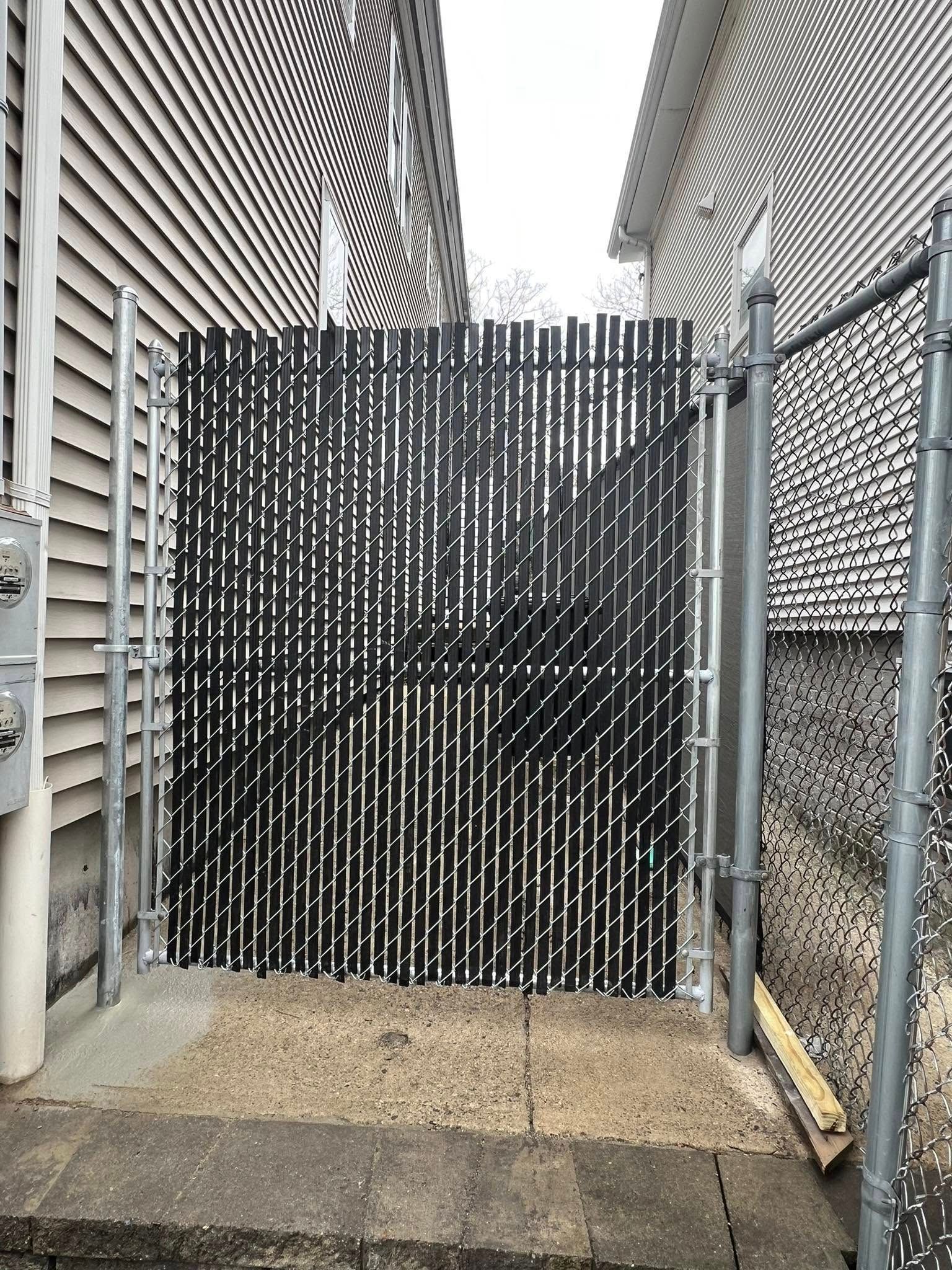 A black chain link fence is between two buildings.