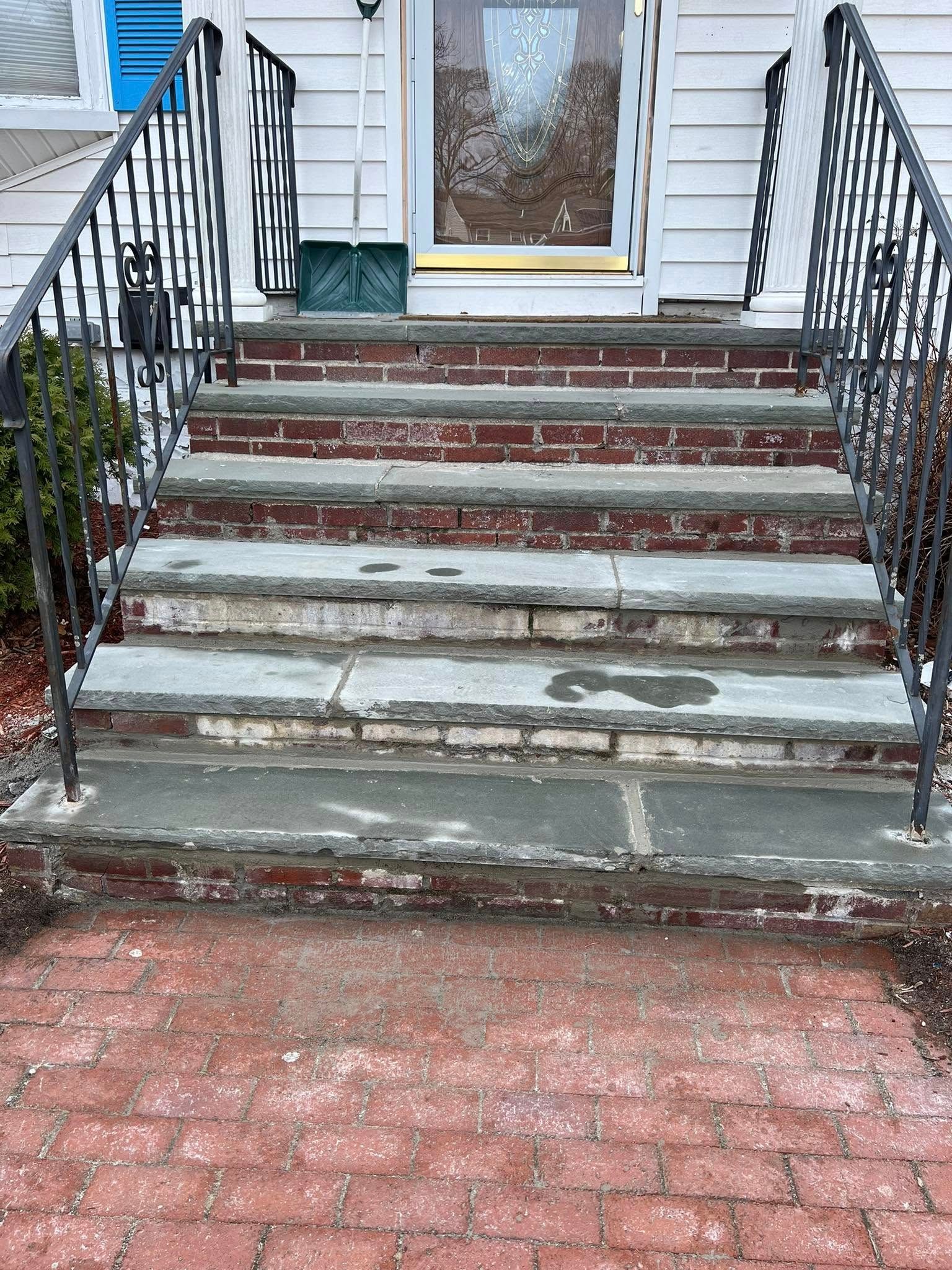 A set of stairs leading up to a house with a wrought iron railing.