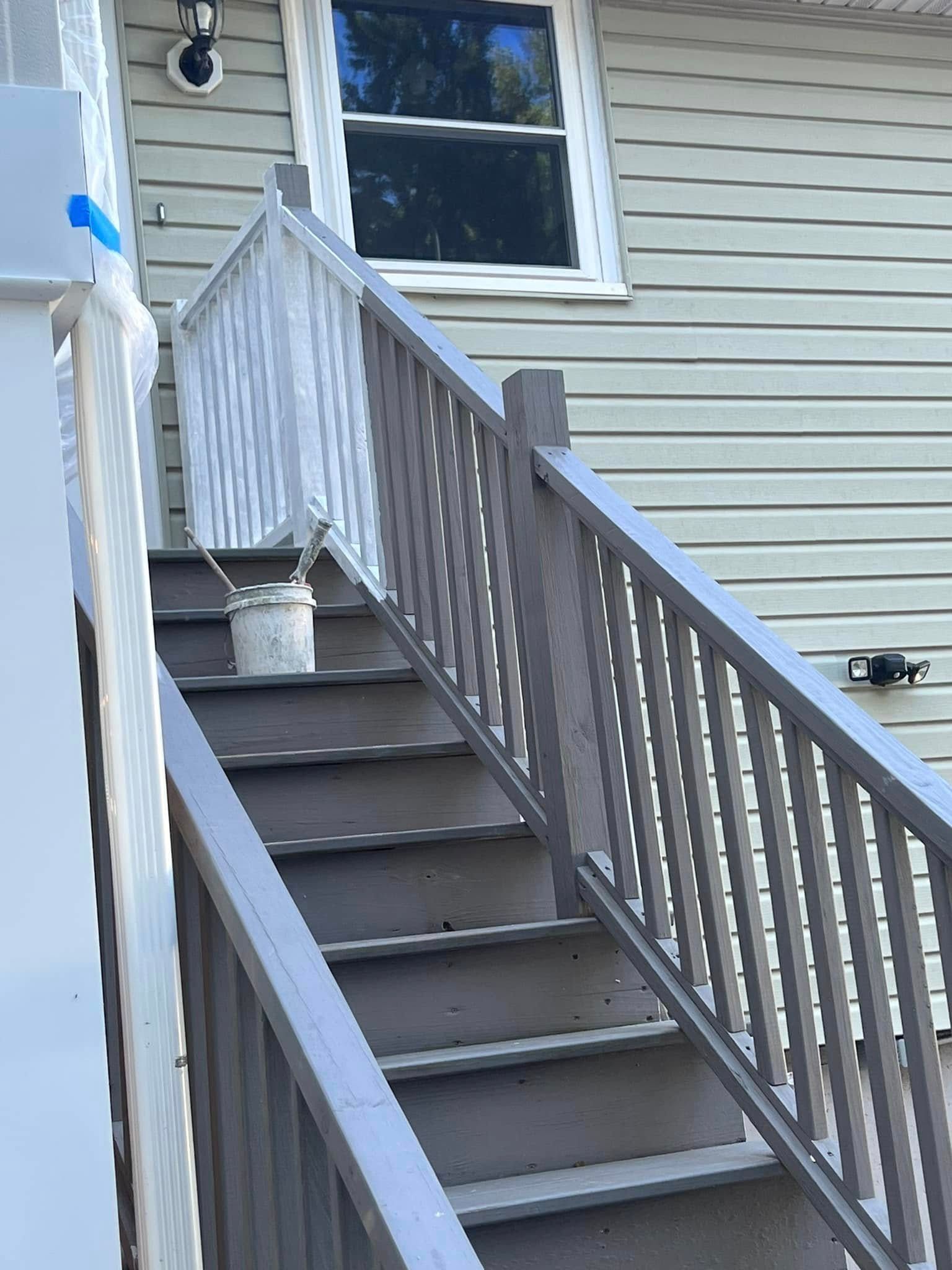 A set of stairs leading up to a house with a white railing.