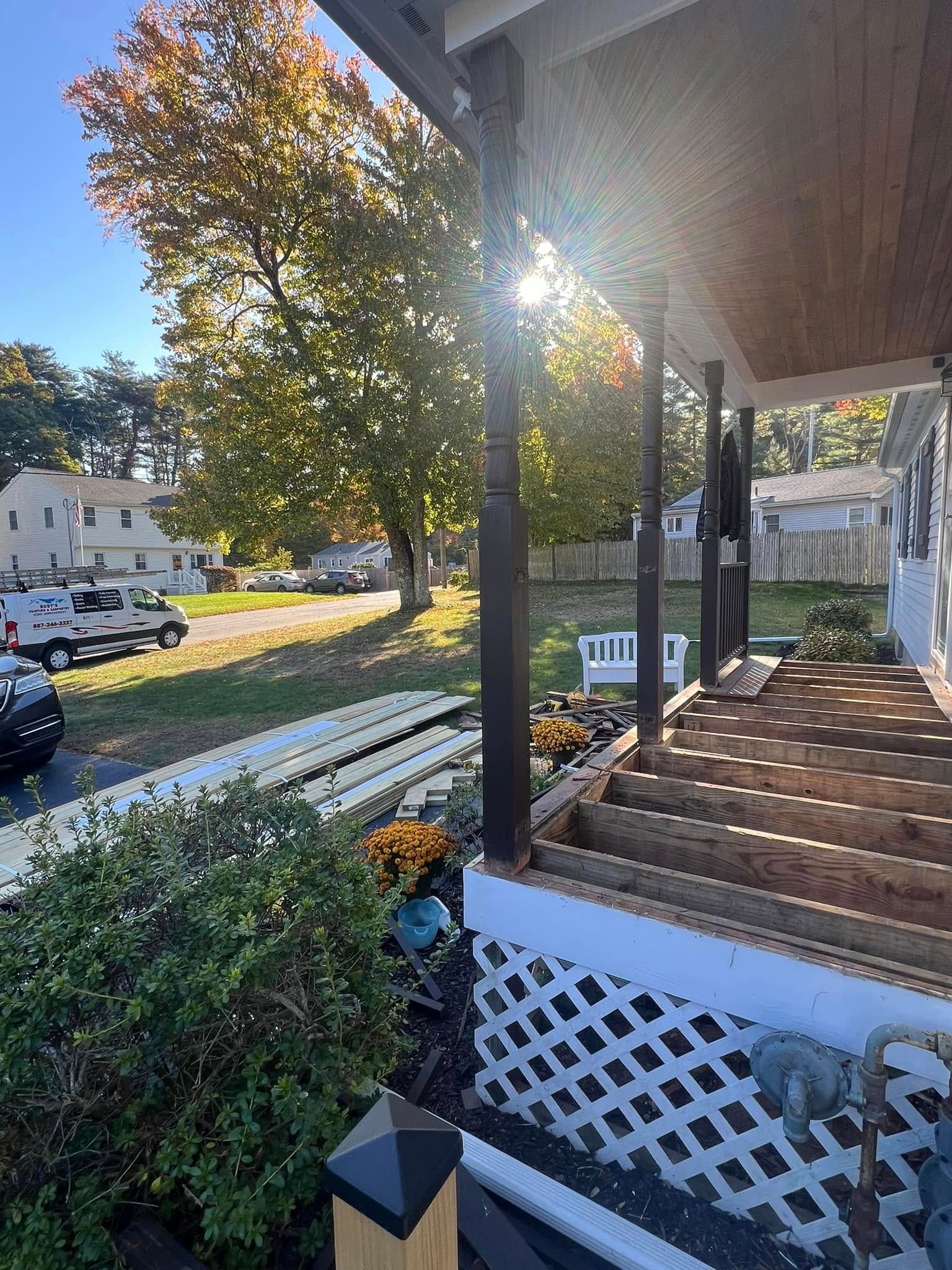 The sun is shining through the trees on the porch of a house.