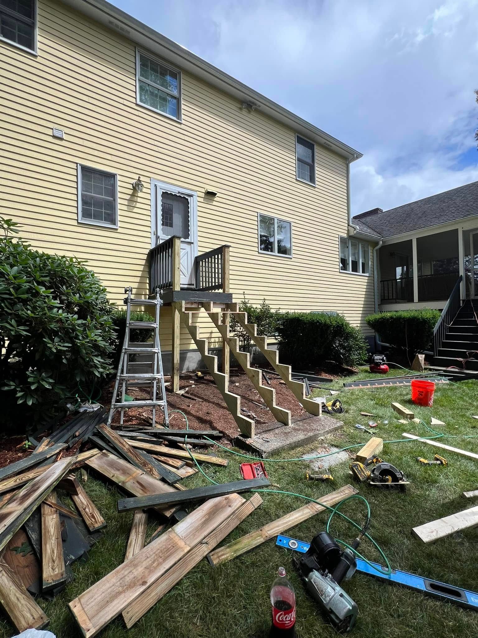 A pile of wood is sitting in front of a house.