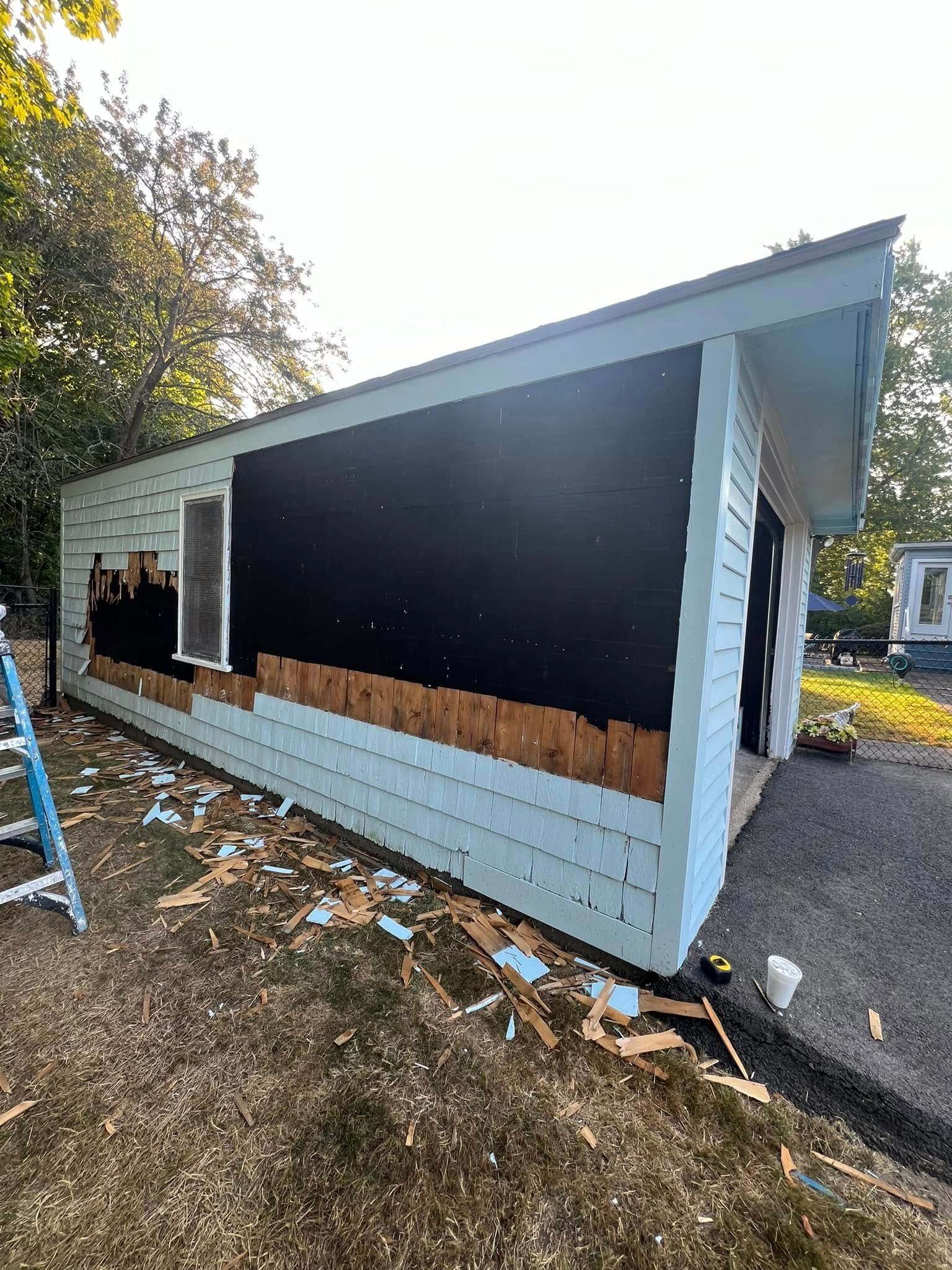 A white house with a black siding is being remodeled.