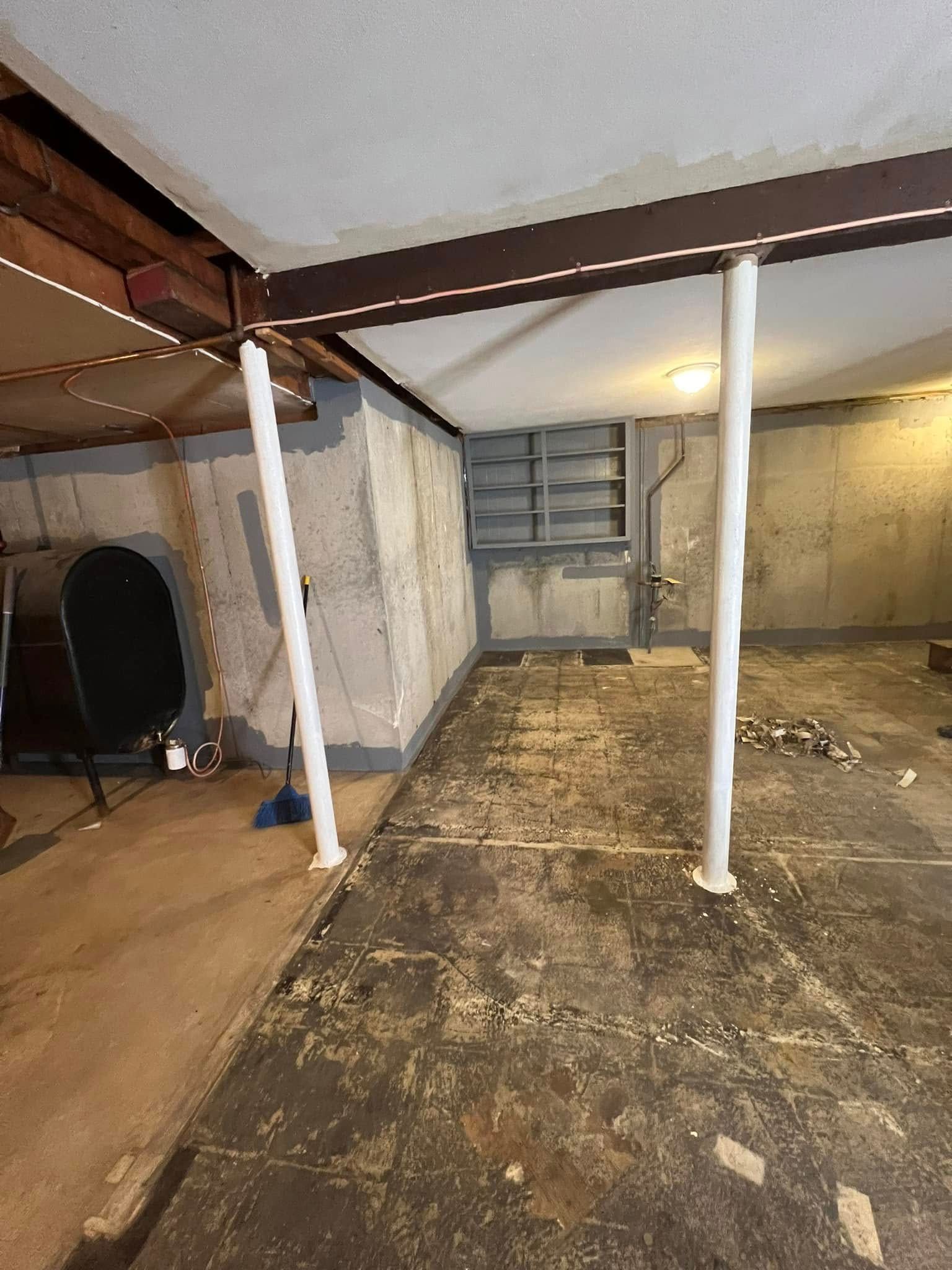 A basement with a staircase and a broom in it.
