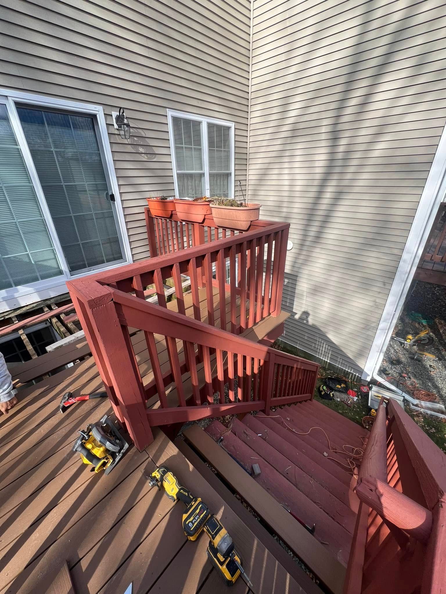 A deck with stairs and a railing is being built on the side of a house.