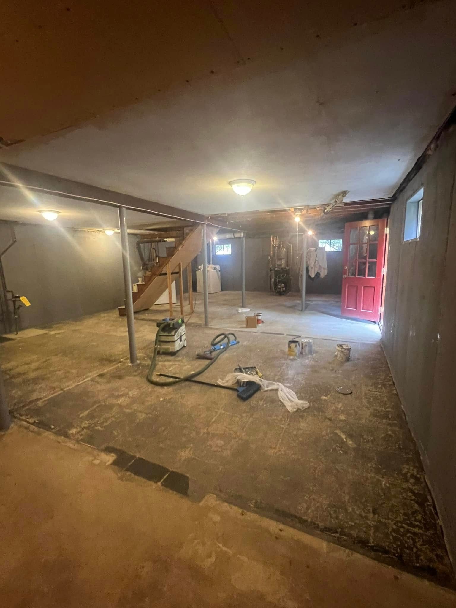 A basement with a staircase and a vacuum cleaner in it.