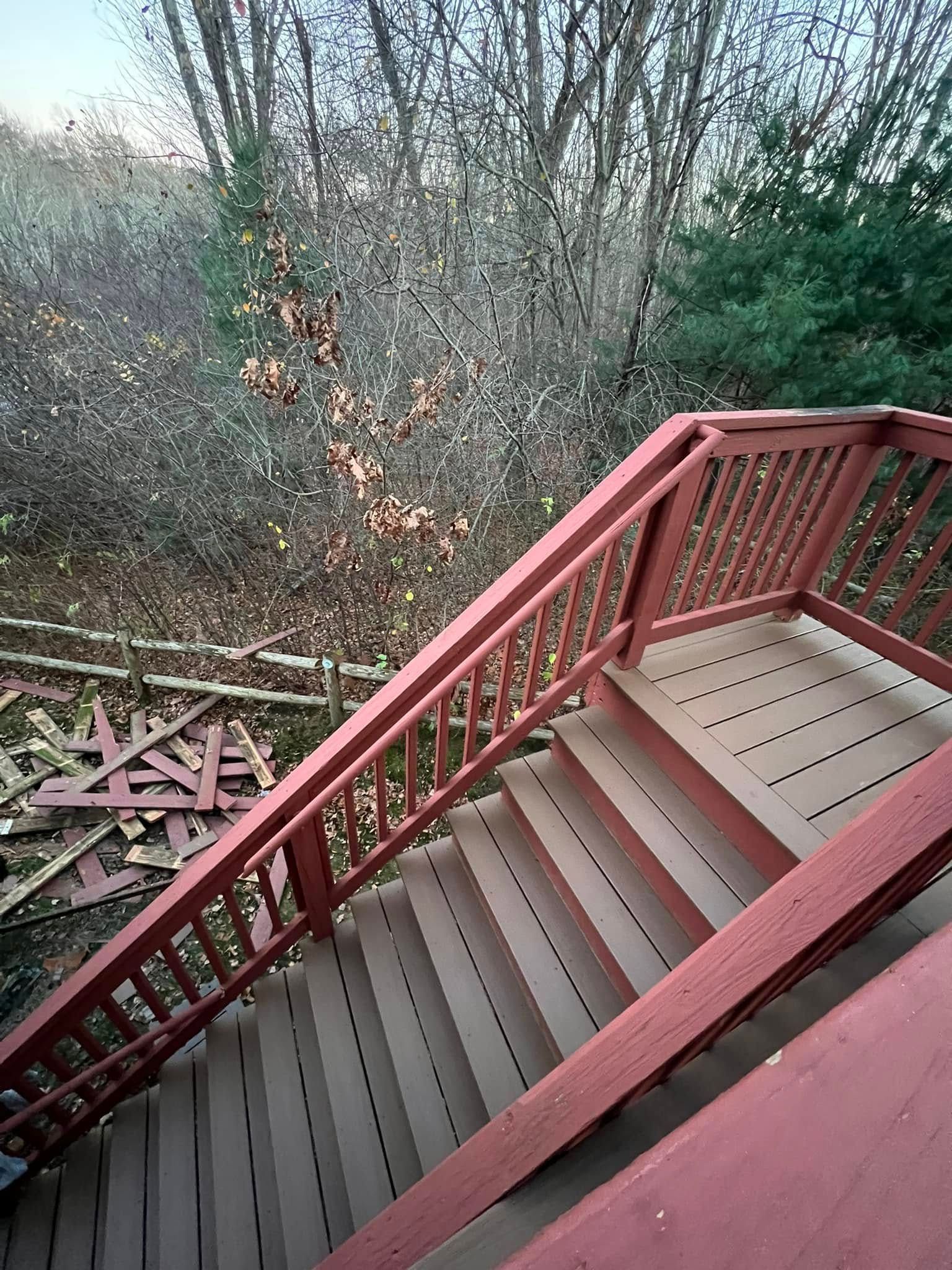 A set of stairs leading up to a deck with a red railing.