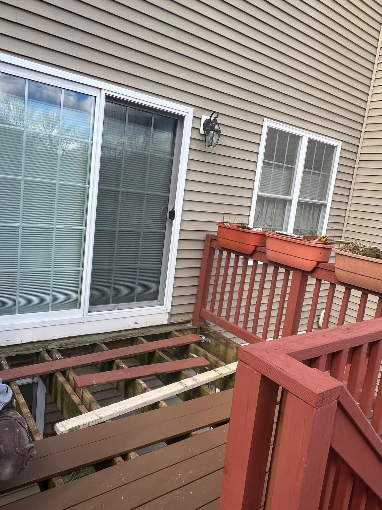 A deck is being built in front of a house with a sliding glass door.