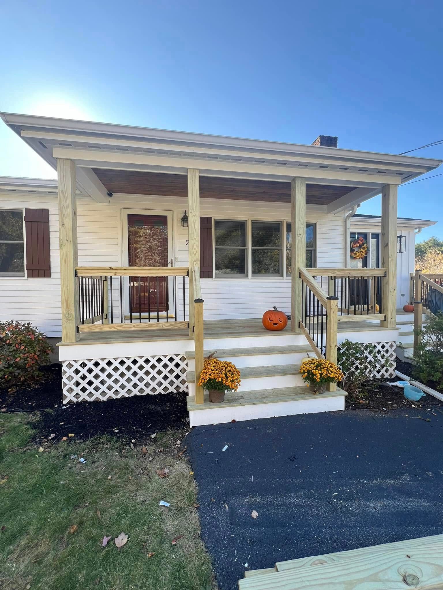 A white house with a porch and a pumpkin on it.