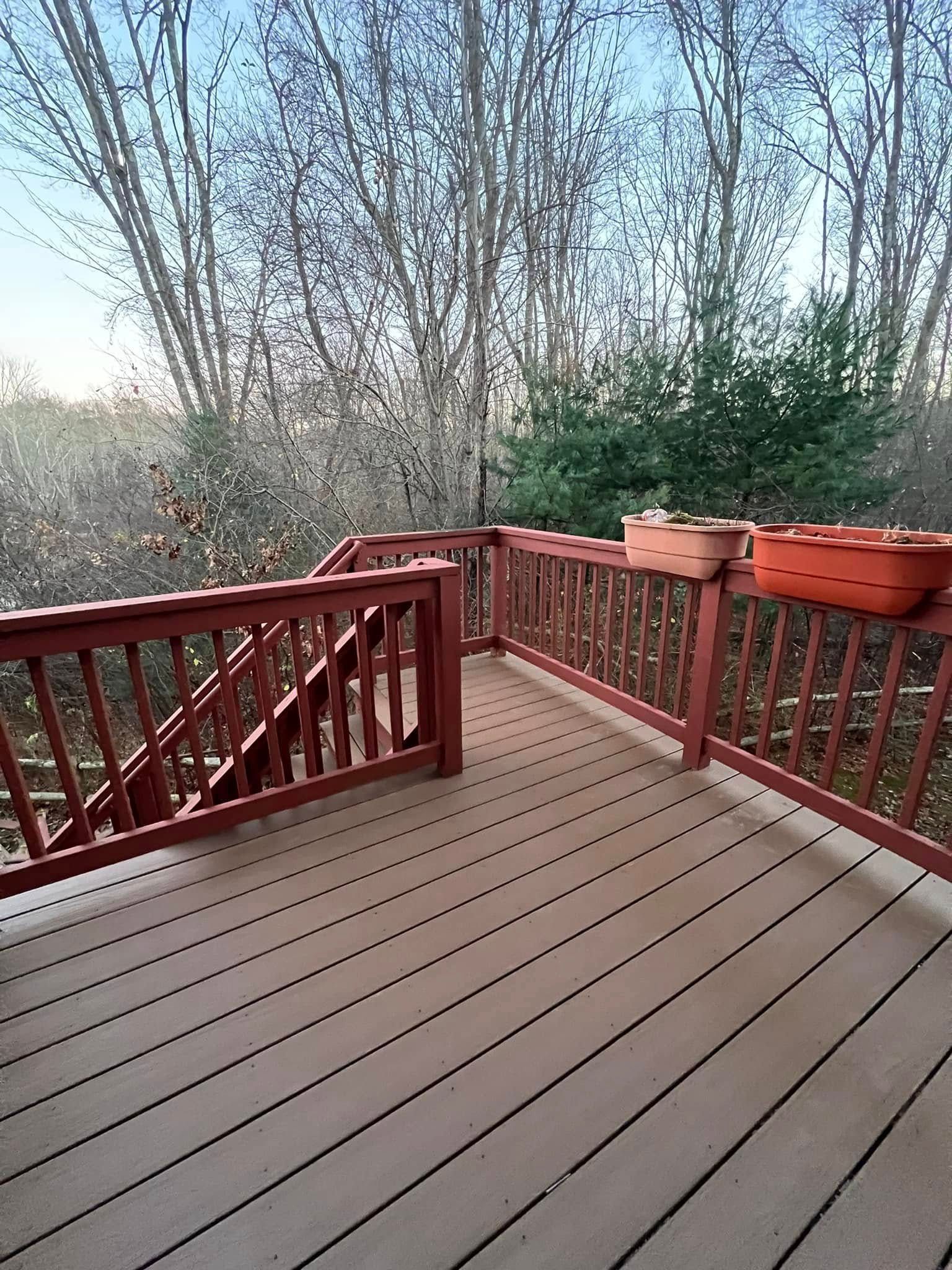 A wooden deck with a red railing and potted plants on it.