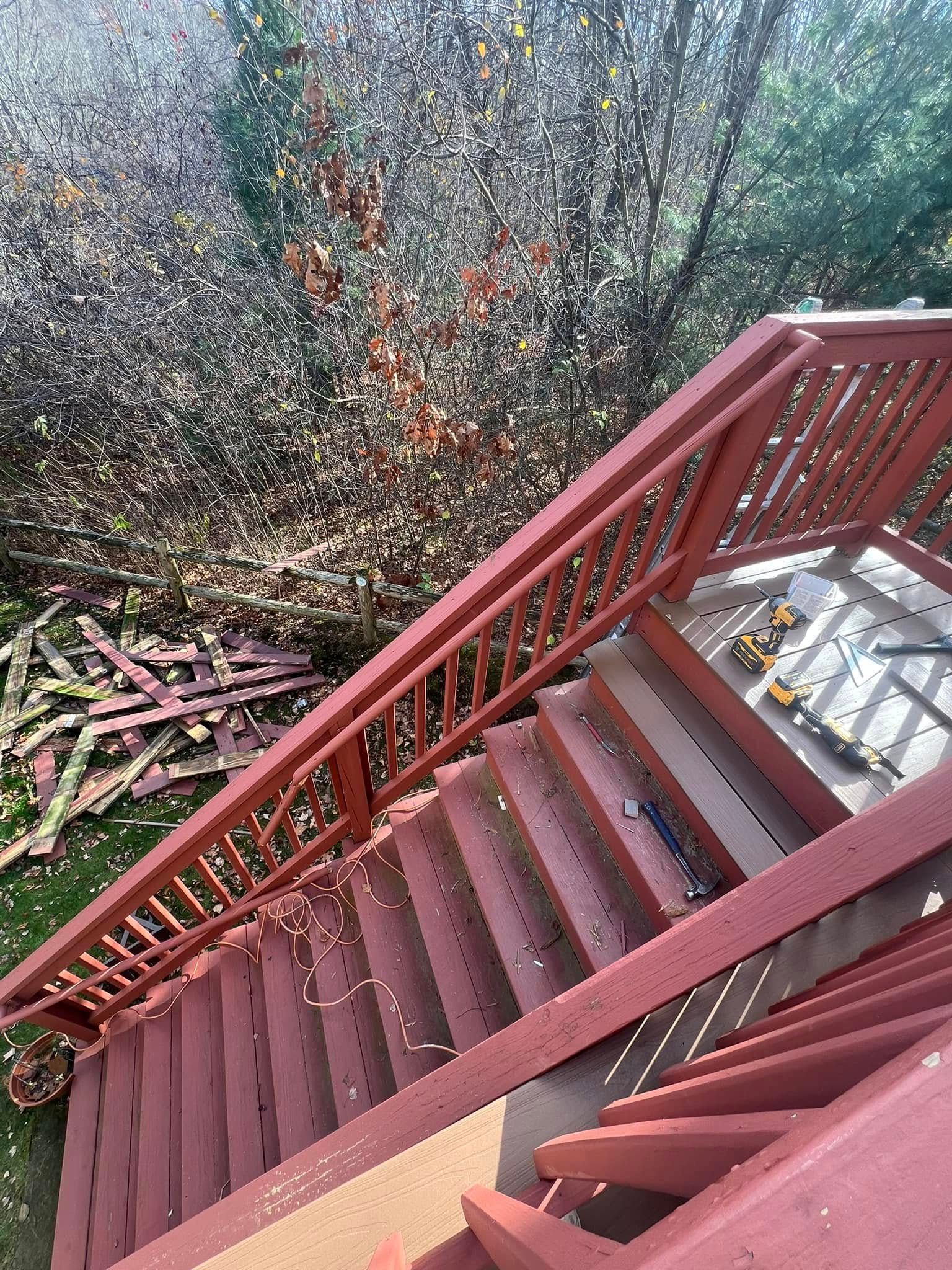 A red wooden deck with stairs and a railing.