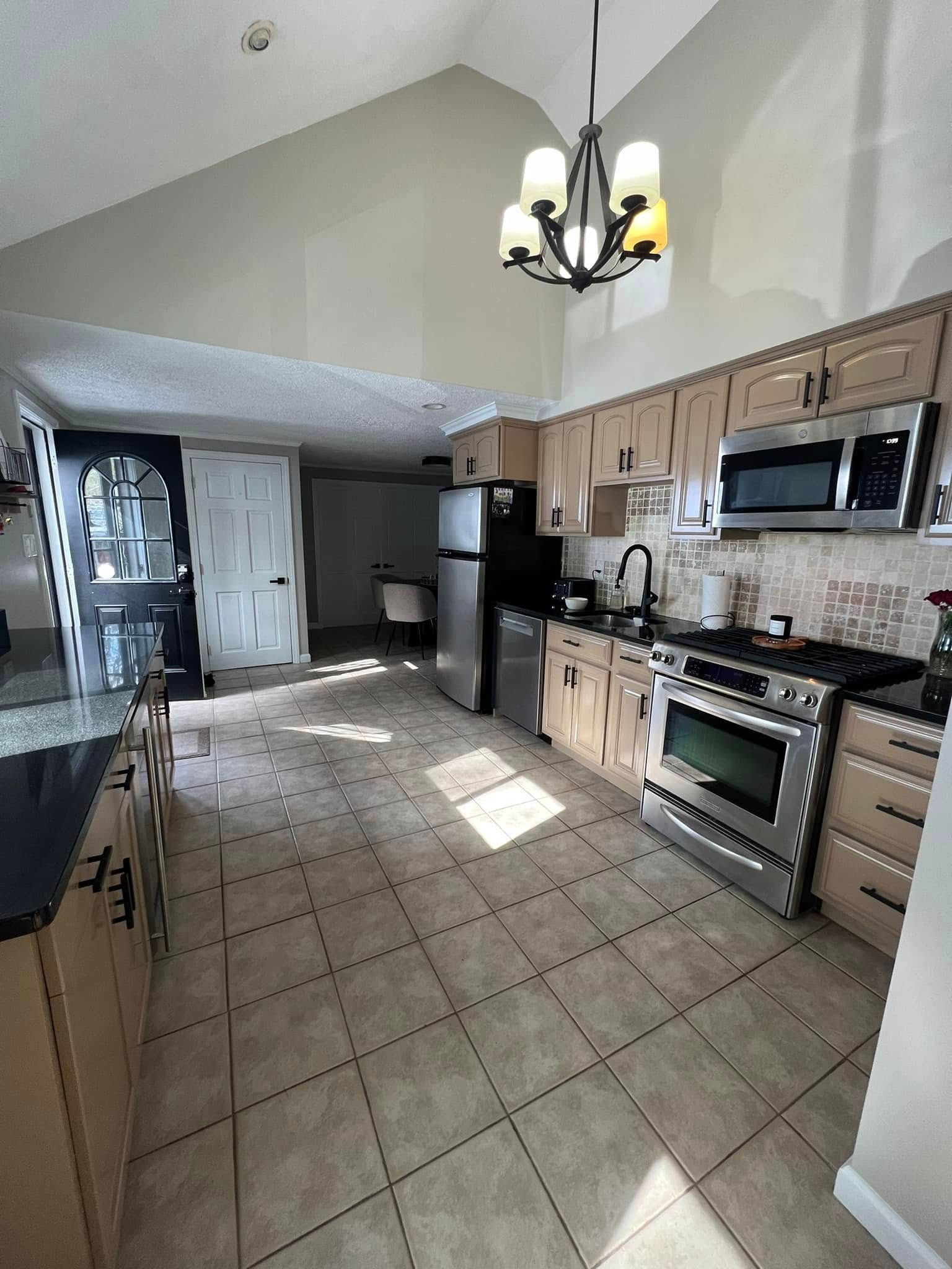A kitchen with stainless steel appliances and a chandelier hanging from the ceiling.