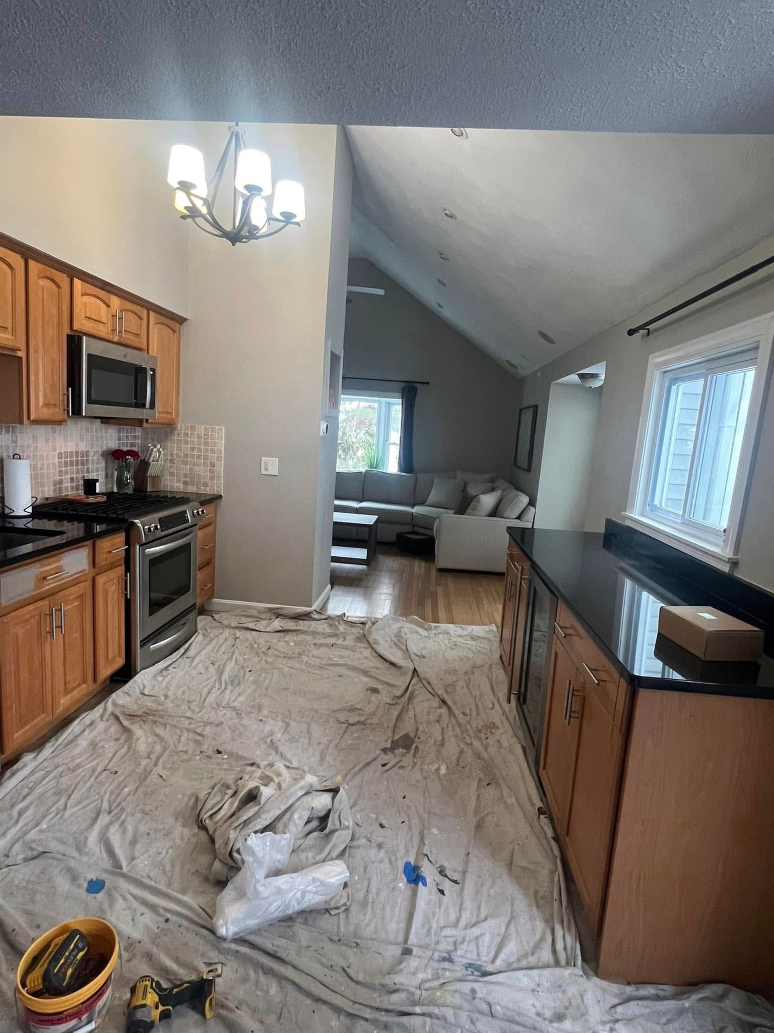 A kitchen with wooden cabinets and a black counter top is being painted.