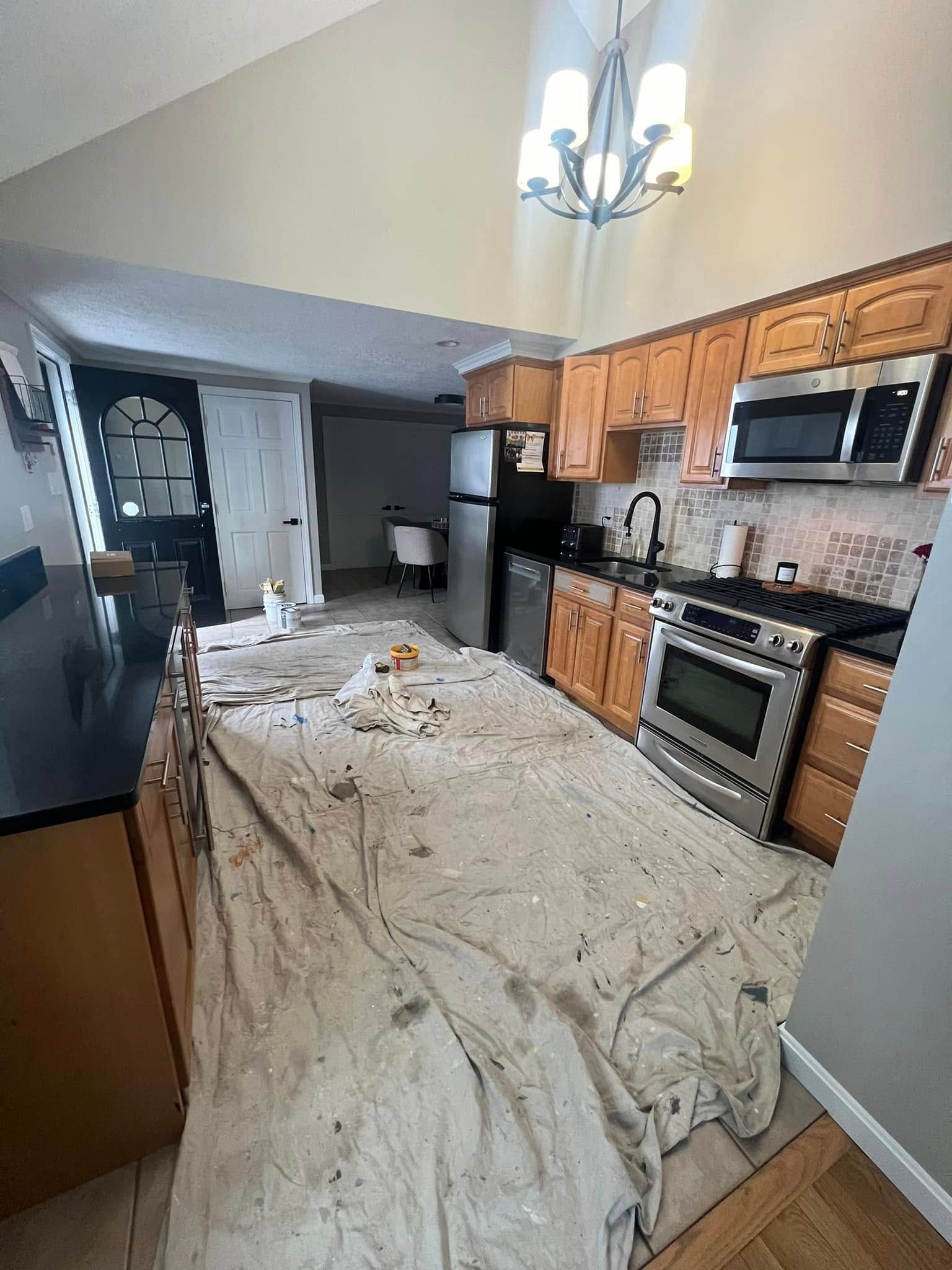 A kitchen with wooden cabinets and stainless steel appliances is being painted.