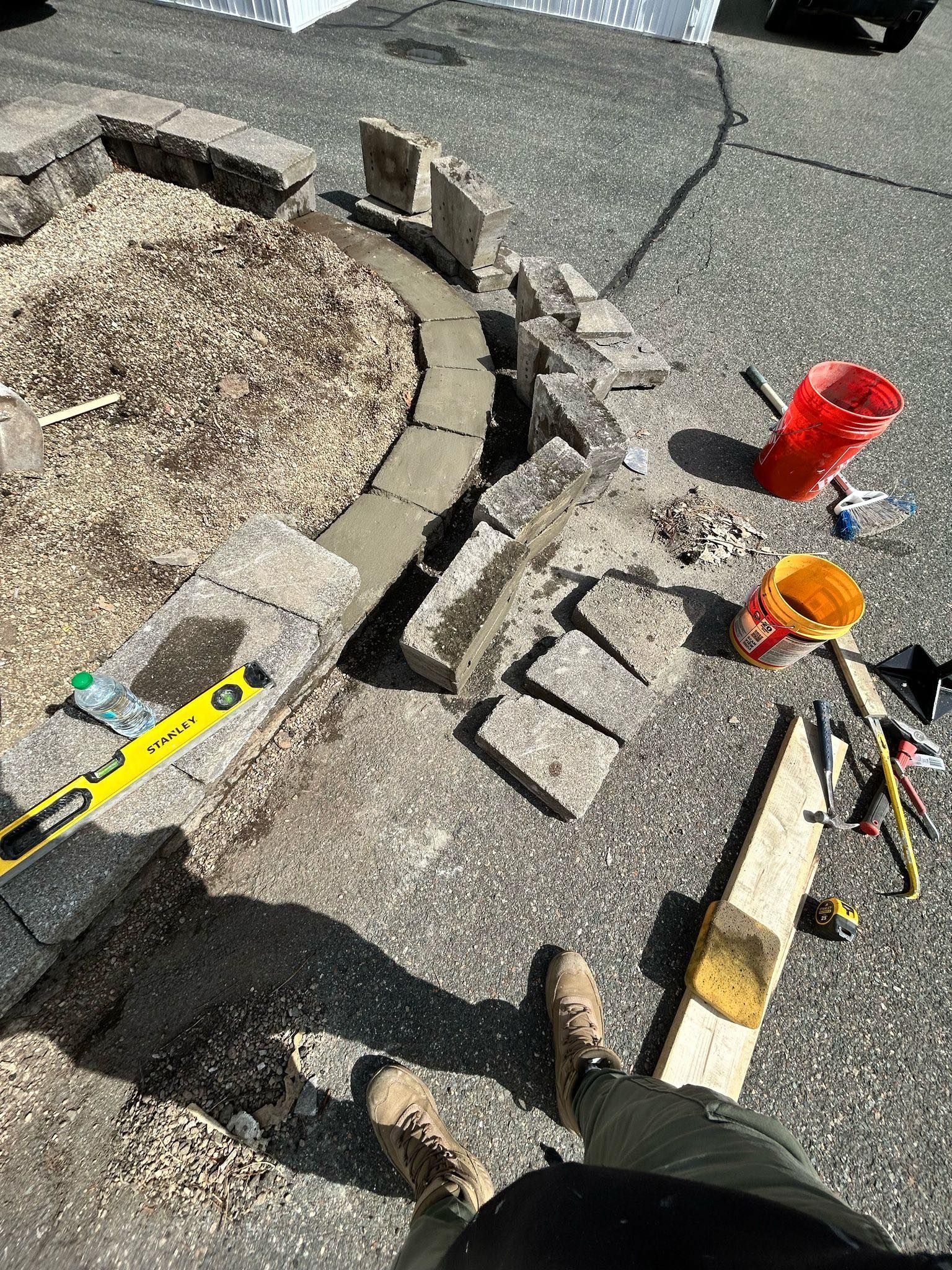 A person is working on a fire pit in a driveway.