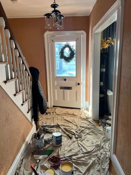 A hallway with a wreath on the door is being painted.