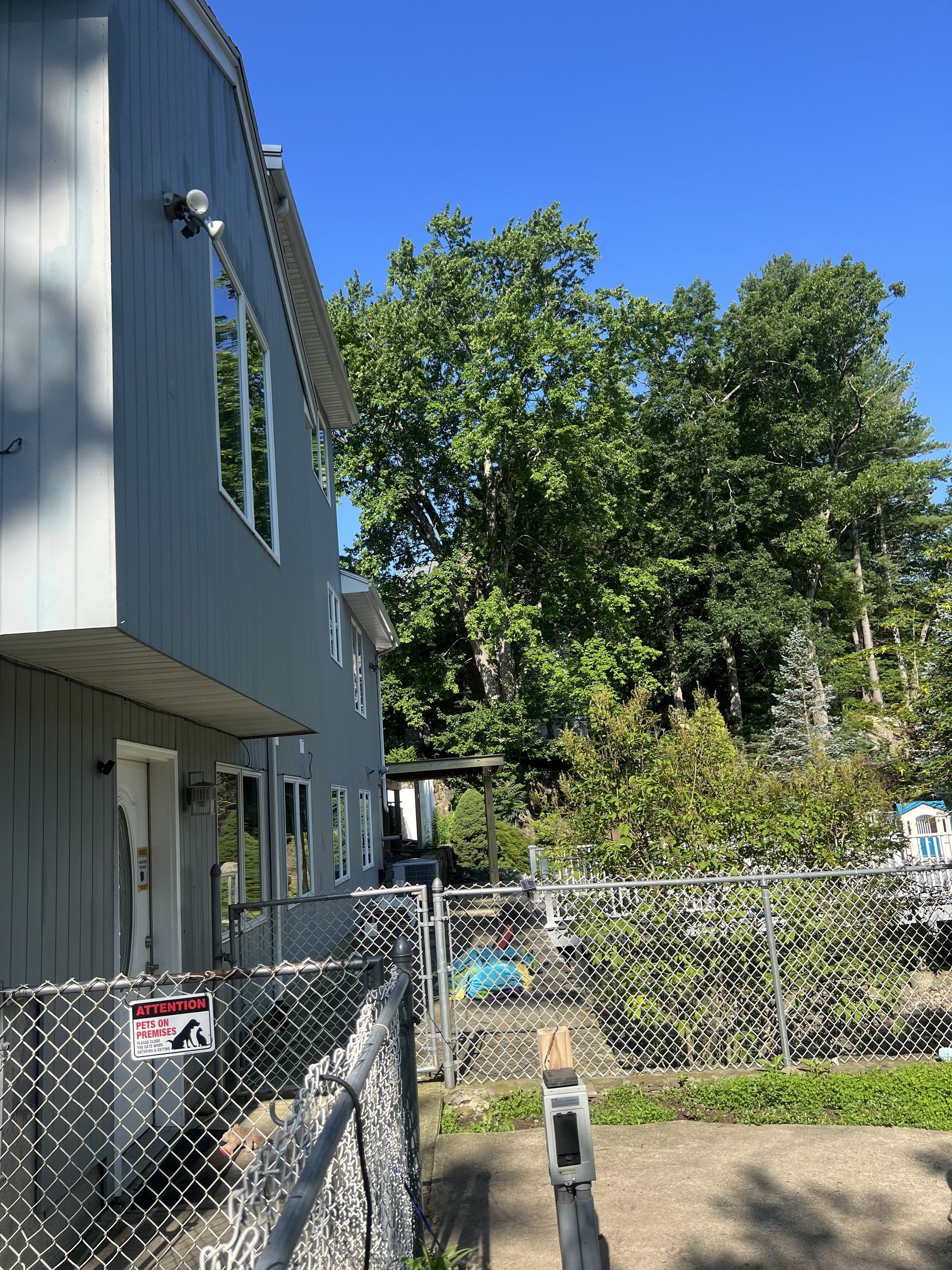 A house with a chain link fence in front of it and trees in the background.