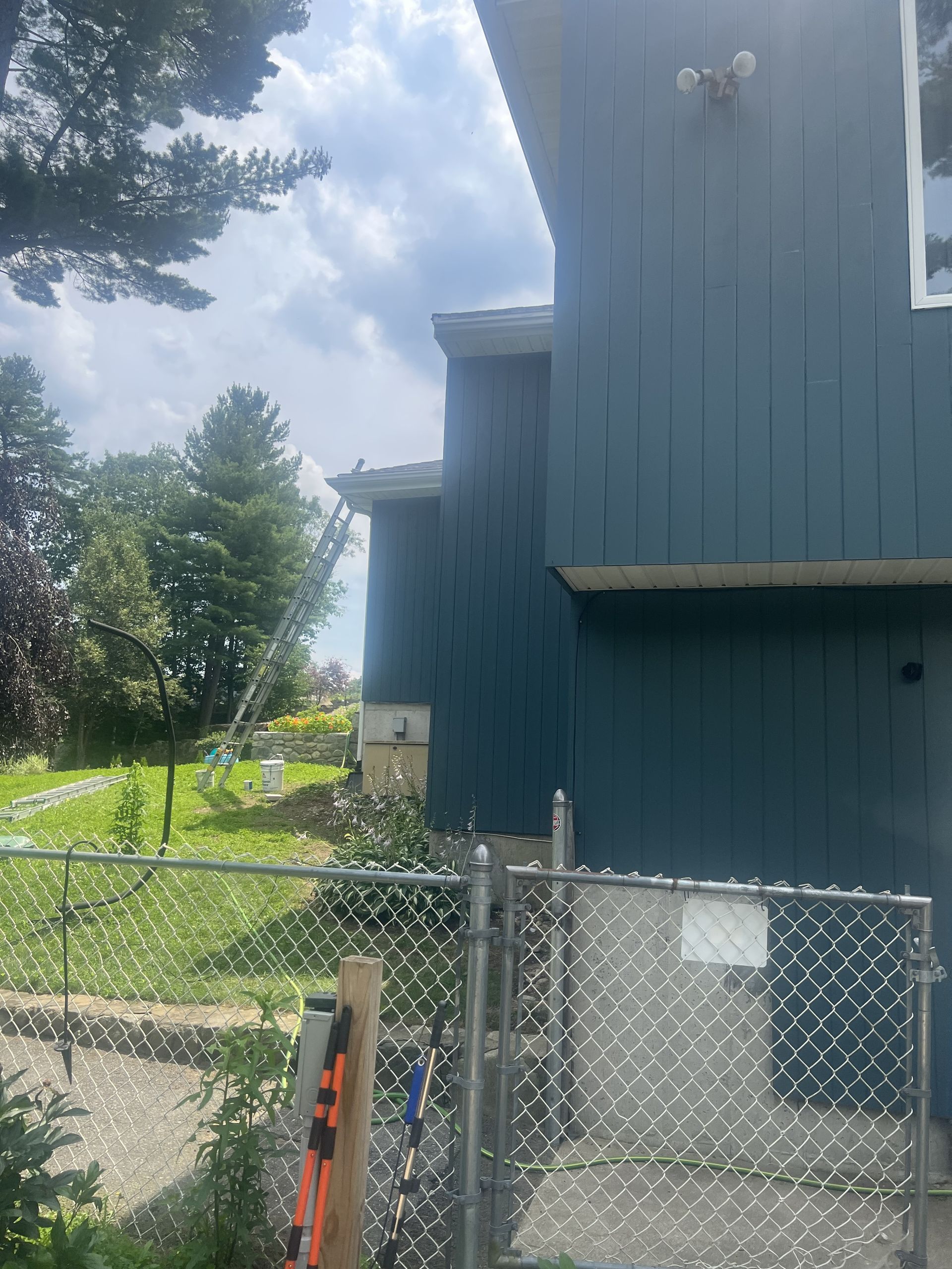 A blue house with a chain link fence in front of it.