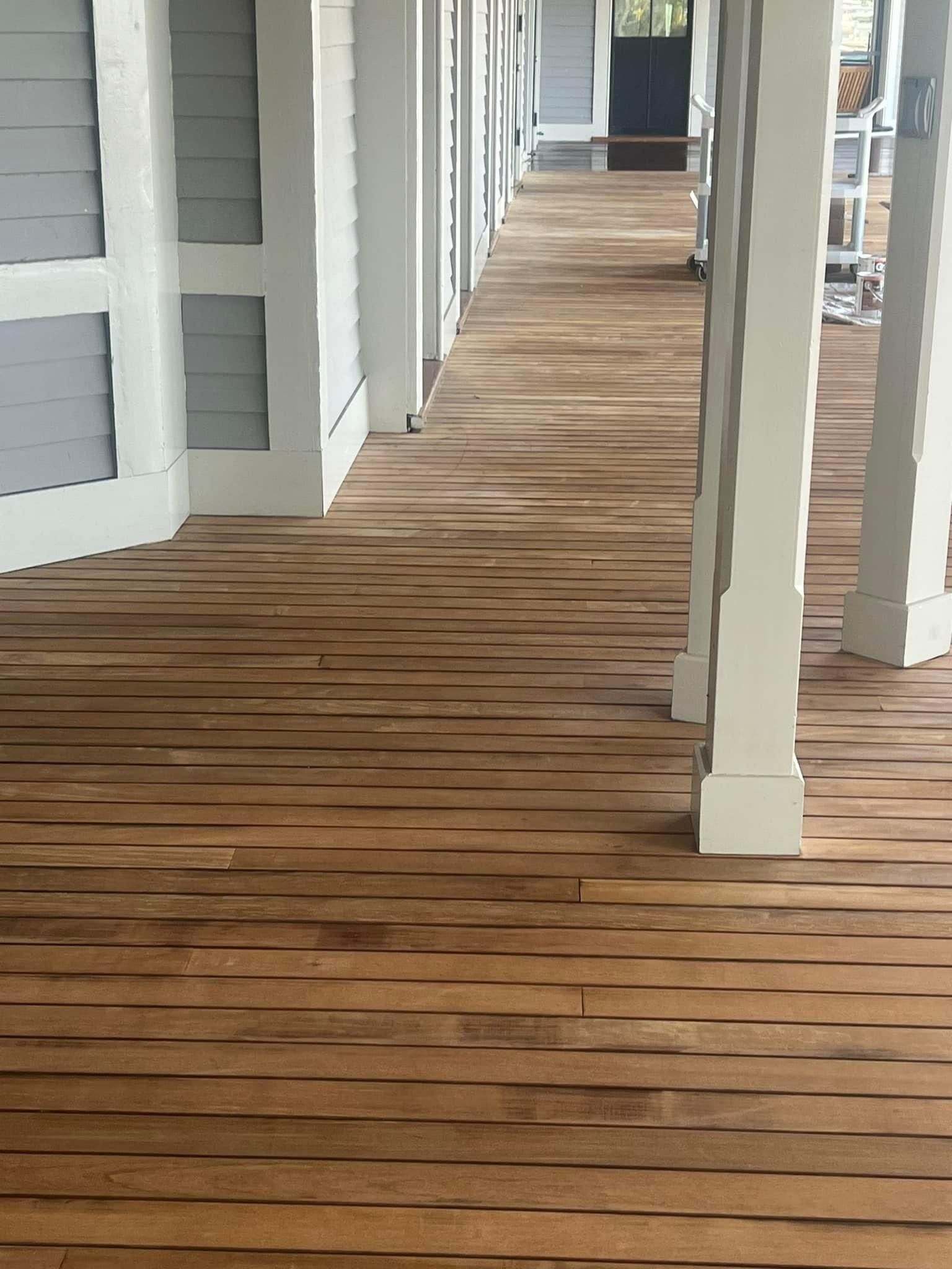 A long wooden walkway between two buildings with white pillars.