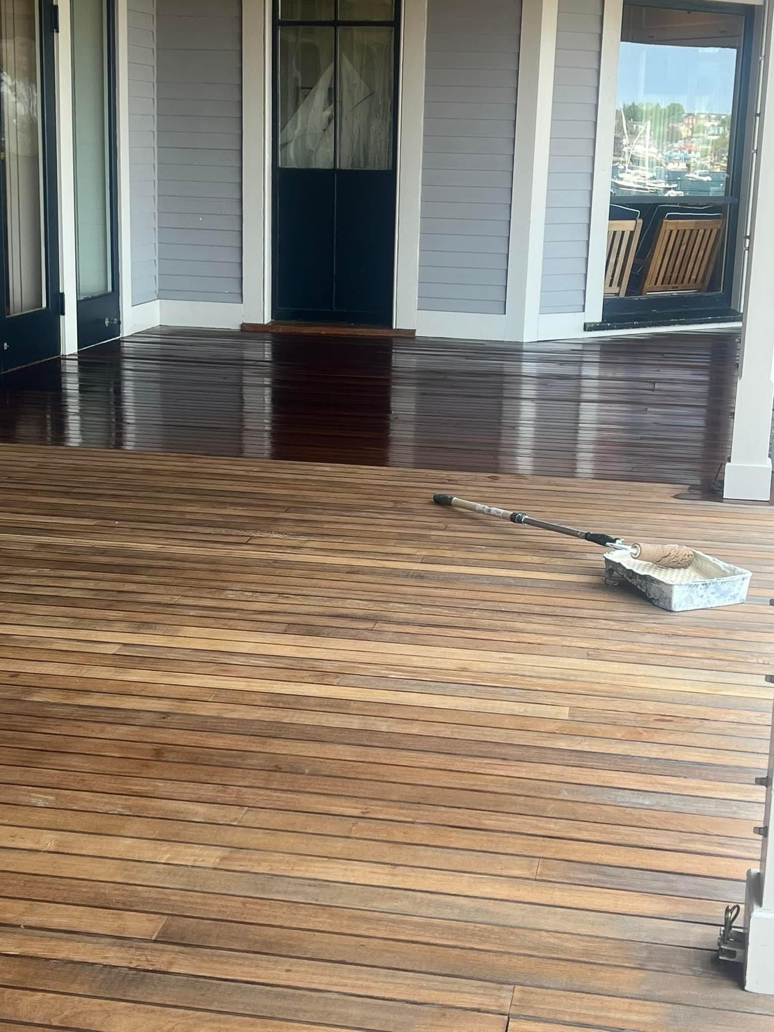 A person is painting a wooden floor with a brush.