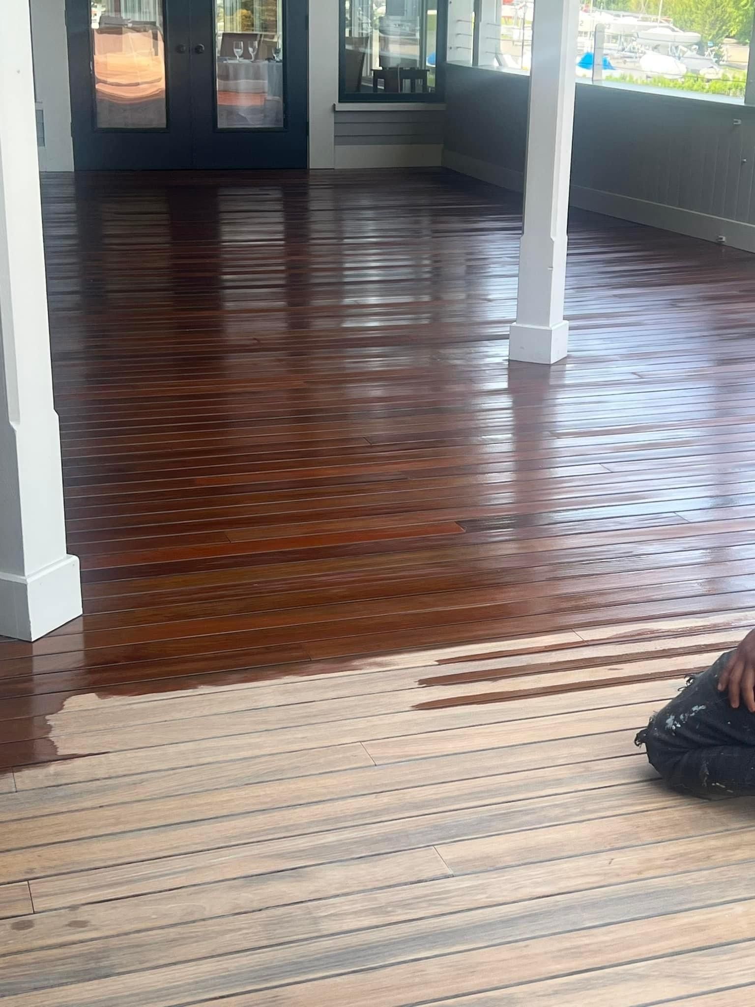 A person is painting a wooden floor in a room