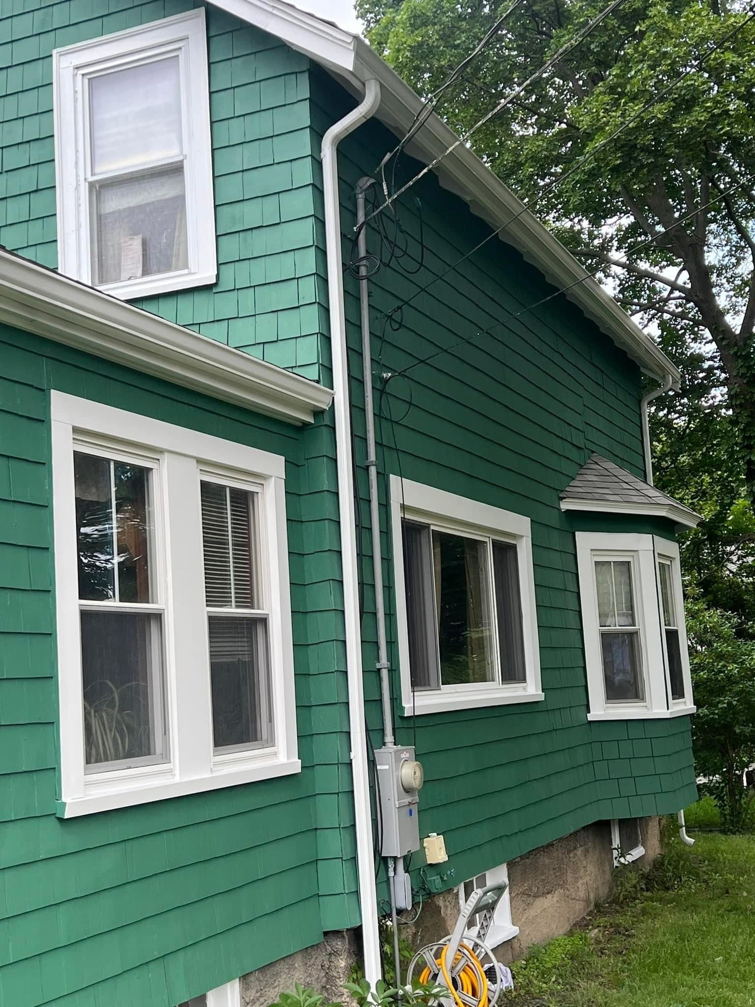 A green house with white windows and a gutter