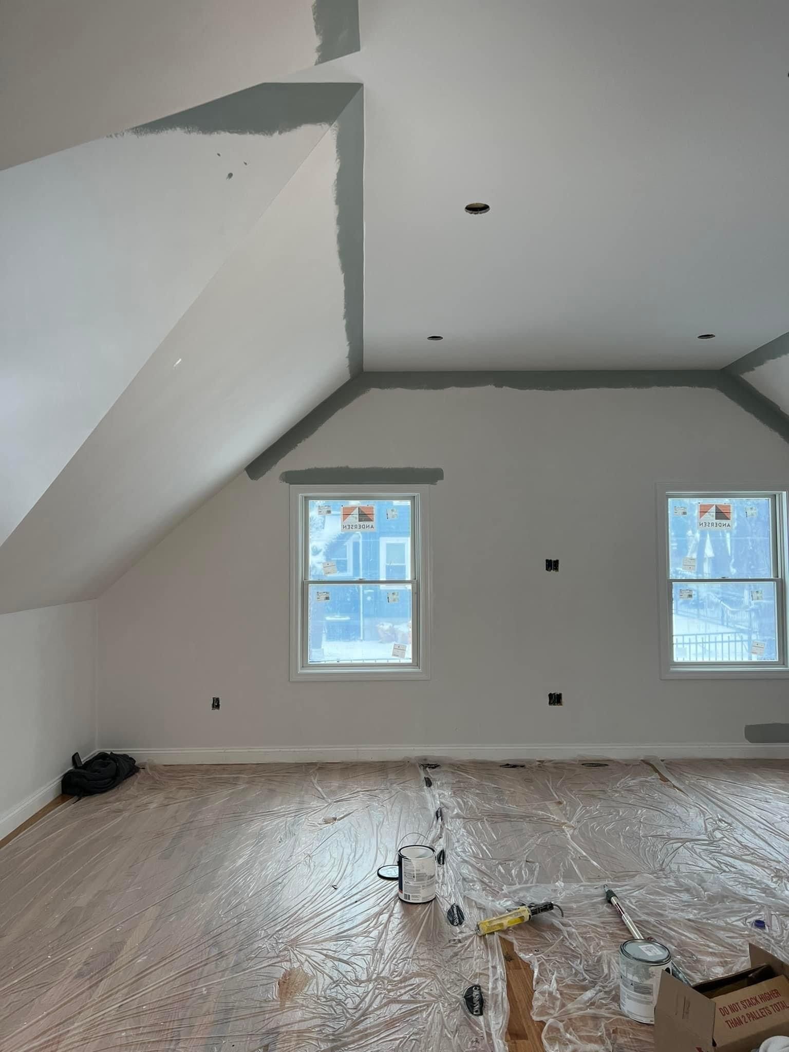 An empty room with a vaulted ceiling and two windows.
