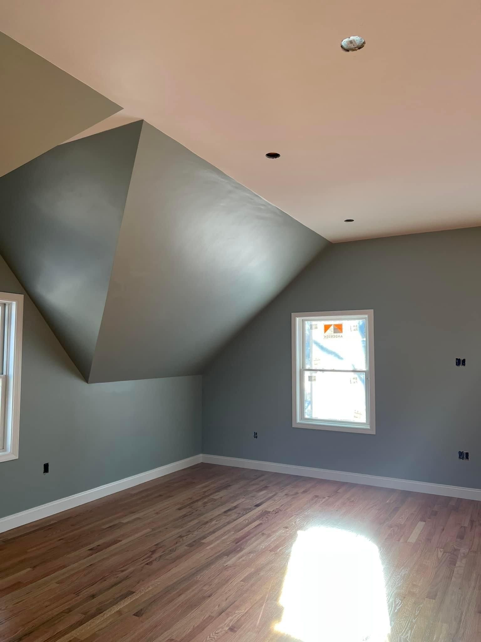 An empty room with a vaulted ceiling and two windows.