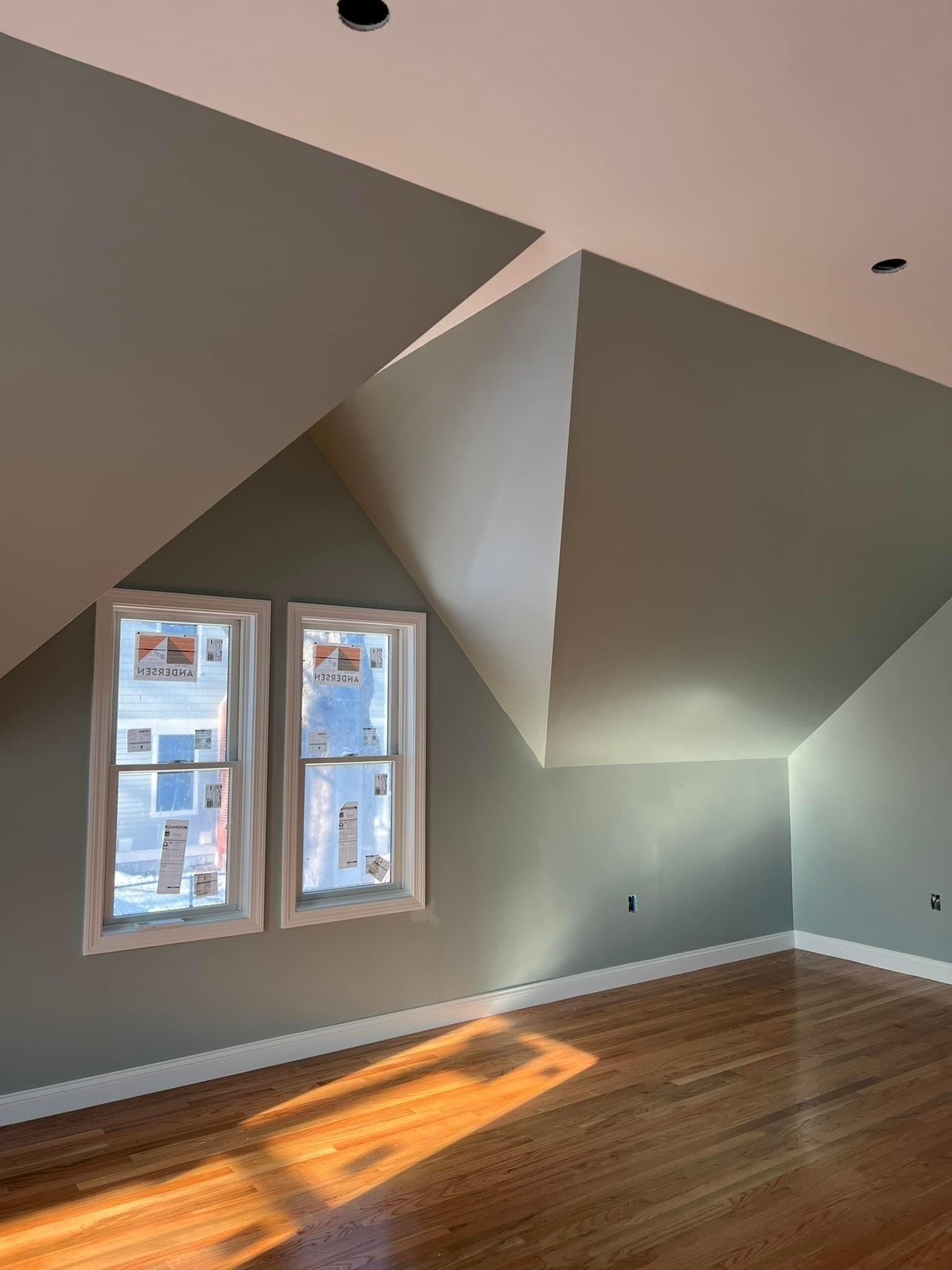 An empty room with a vaulted ceiling and two windows