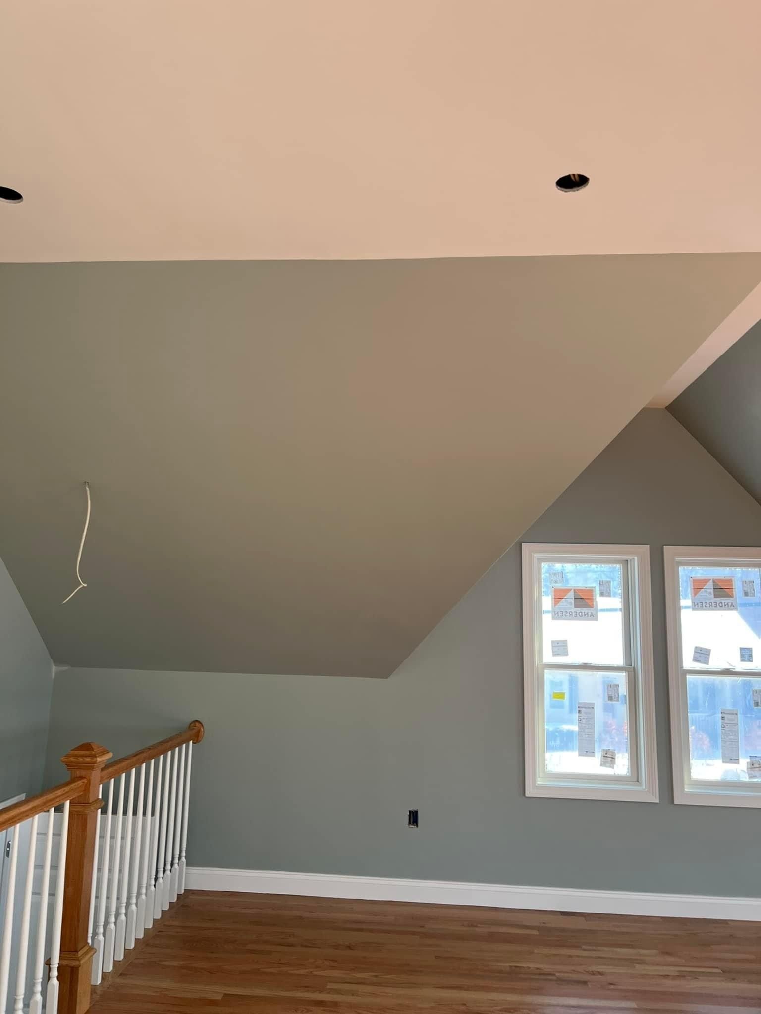 An empty room with a vaulted ceiling and two windows