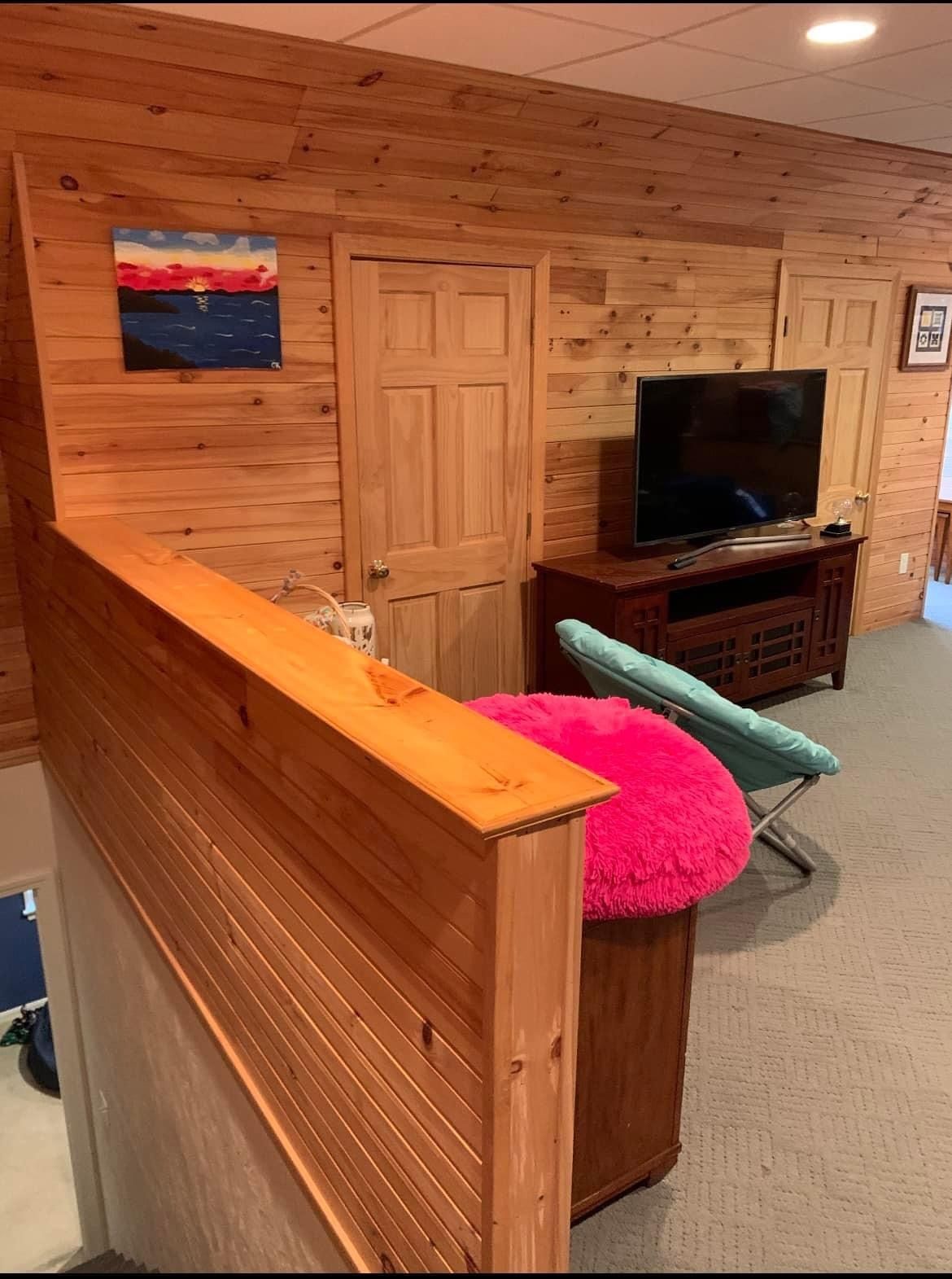 A living room with a pink chair and a flat screen tv