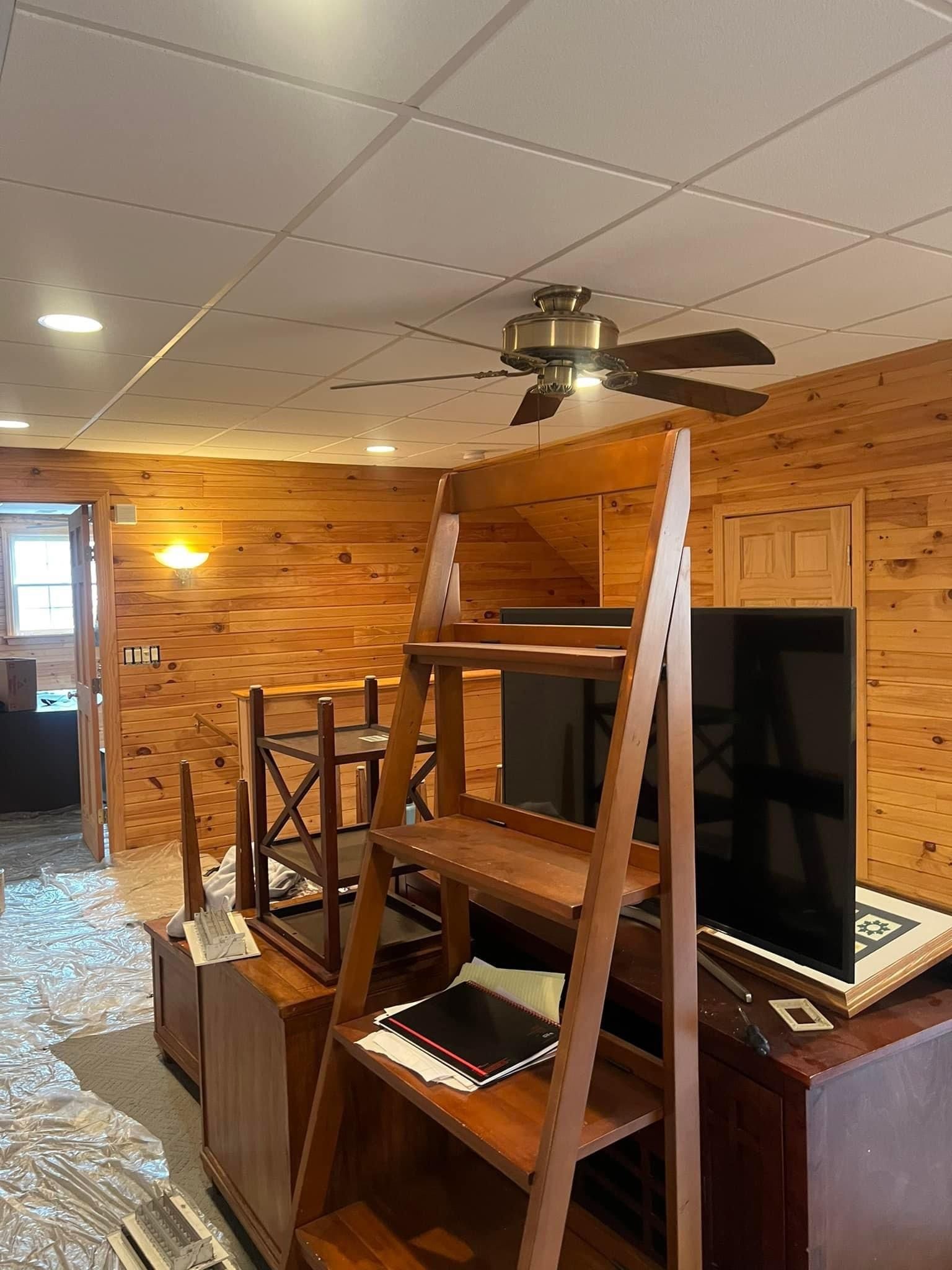 A living room with wooden walls and a ceiling fan.