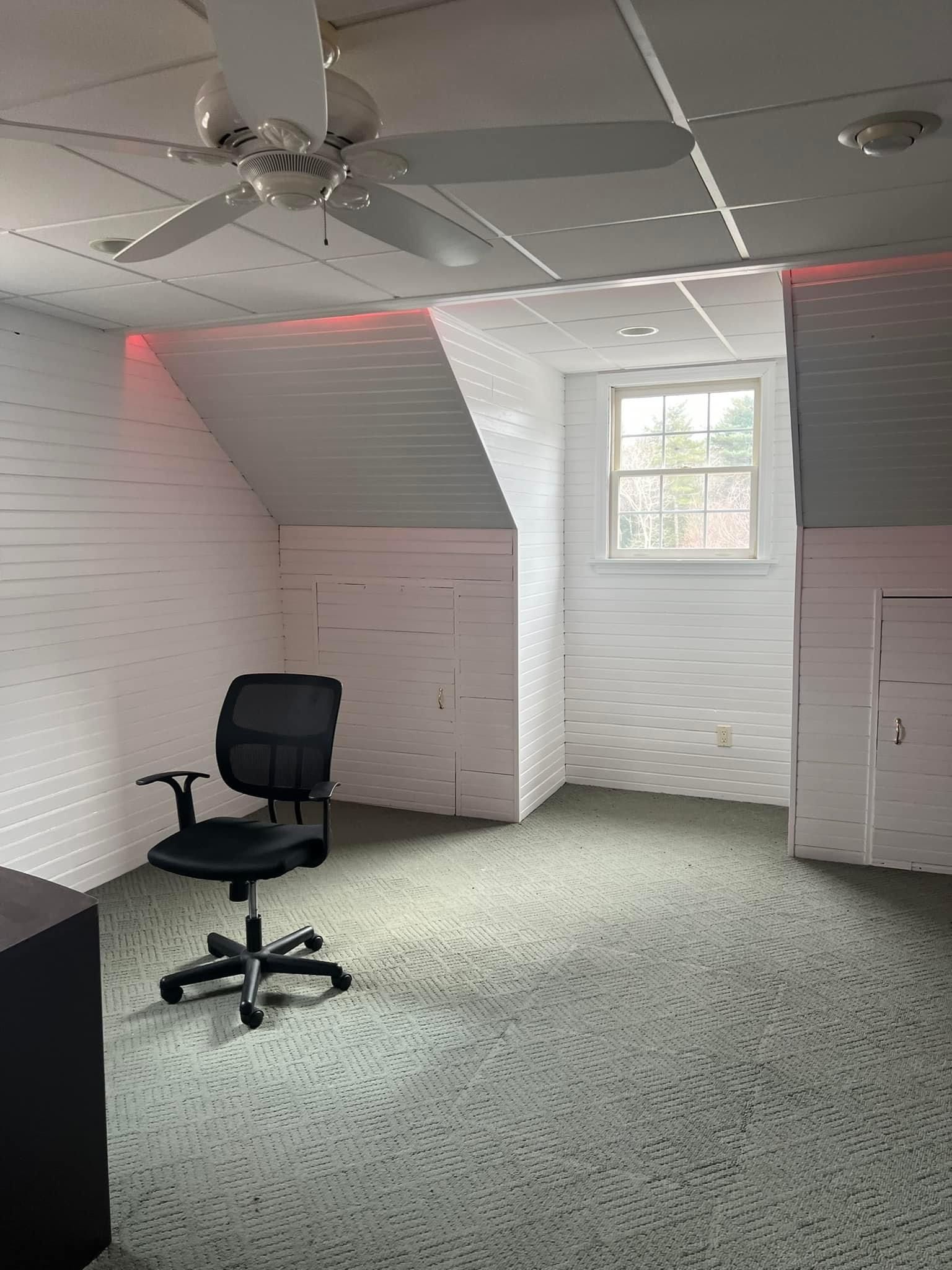An empty room with a chair and a ceiling fan.