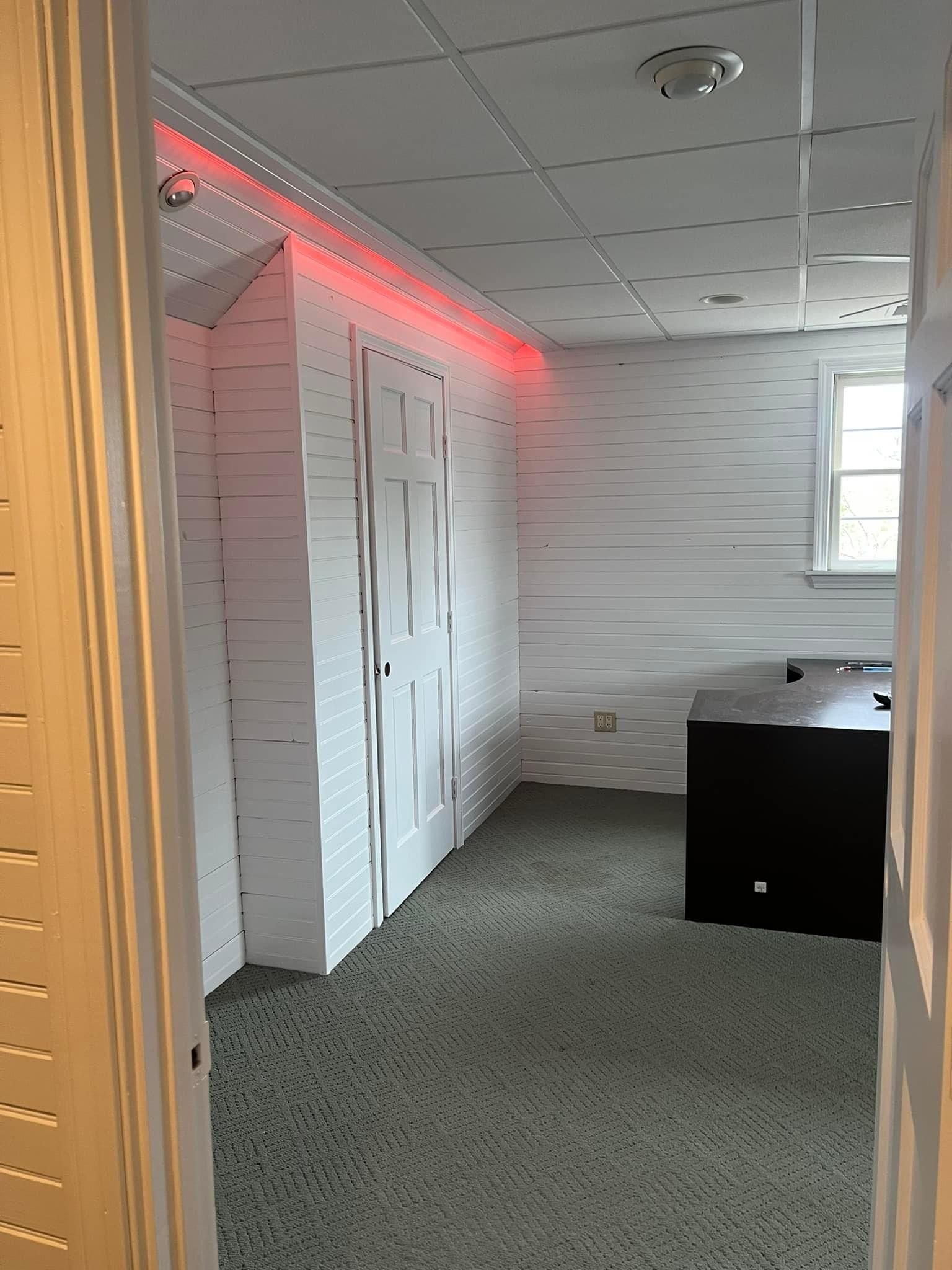 A room with a desk and a red light on the ceiling.