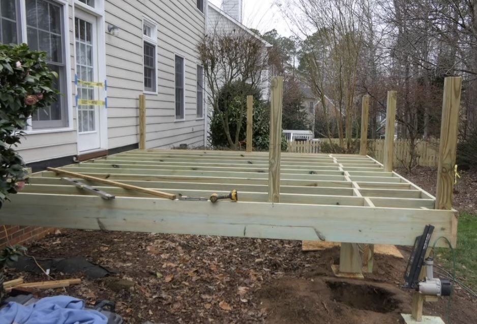 A wooden deck is being built in front of a house.