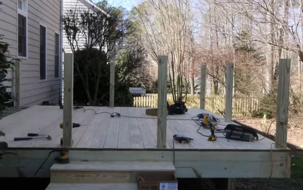 A wooden deck is being built in the backyard of a house.