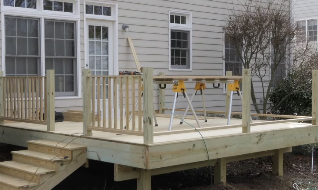 A wooden deck is being built in front of a house.