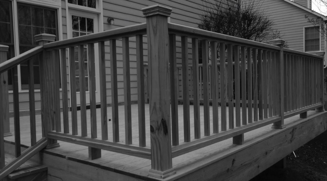 A black and white photo of a wooden deck with a railing.