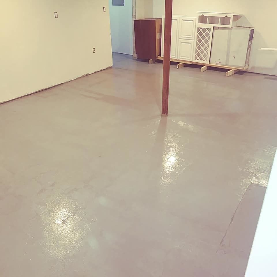 A basement with a concrete floor and a wooden pole.