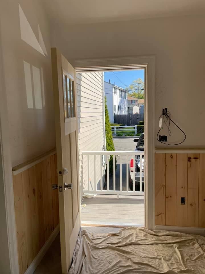 A room with a door open and a view of a house.