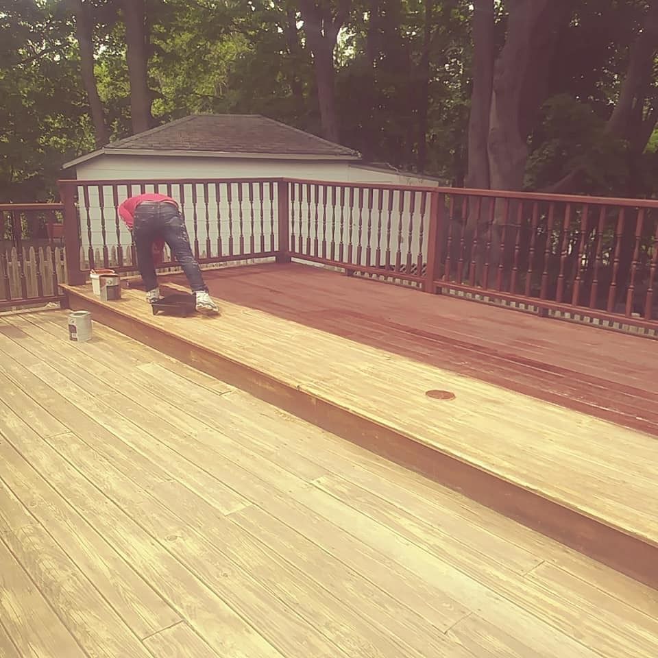 A man is painting a wooden deck with a brush