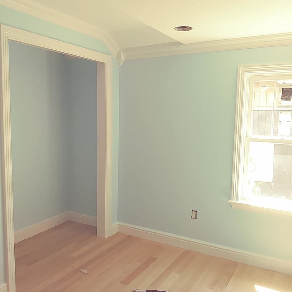 An empty room with light blue walls and a window.