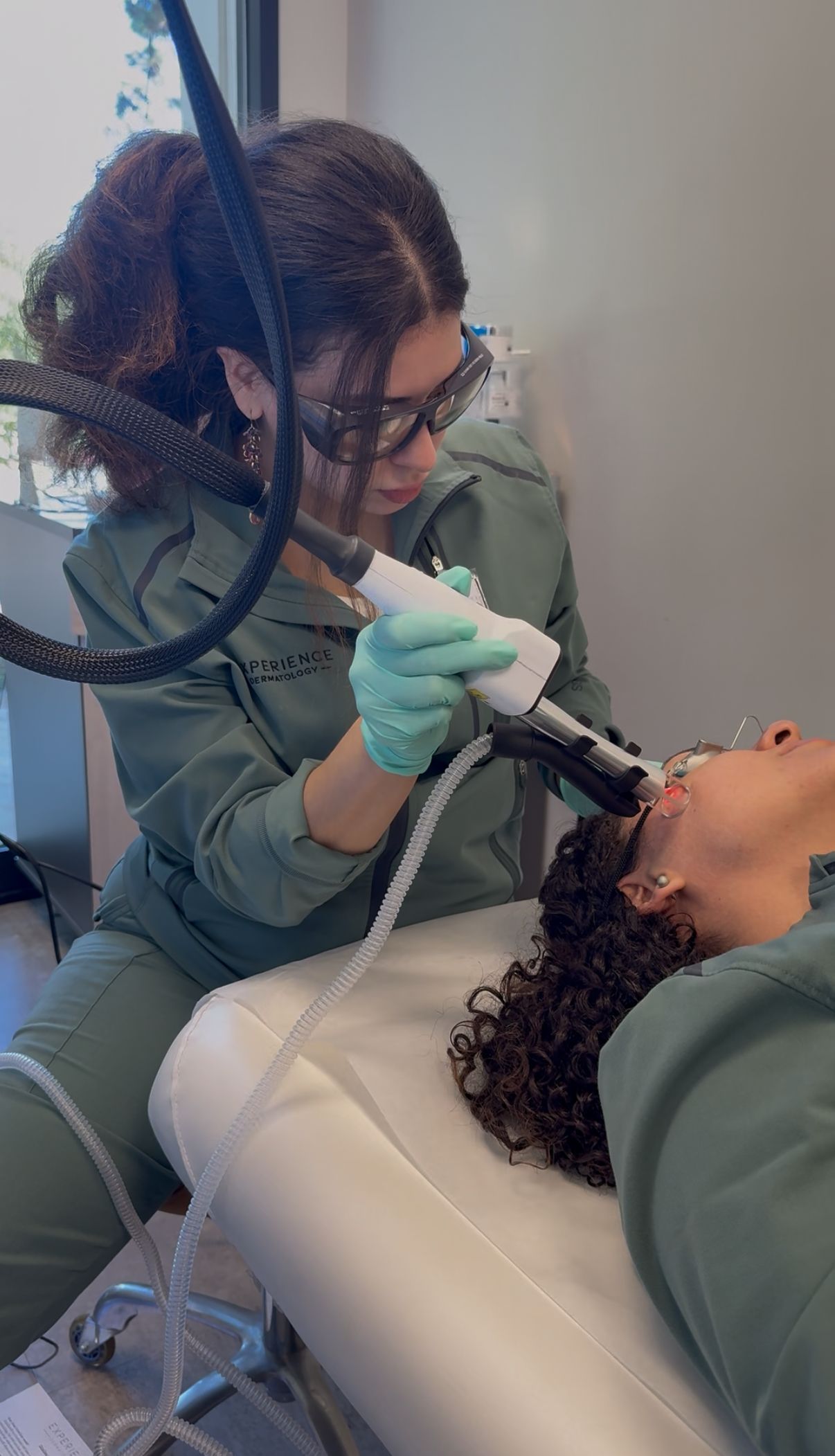 Woman receiving laser hair removal treatment on her cheek, wearing protective eyewear.