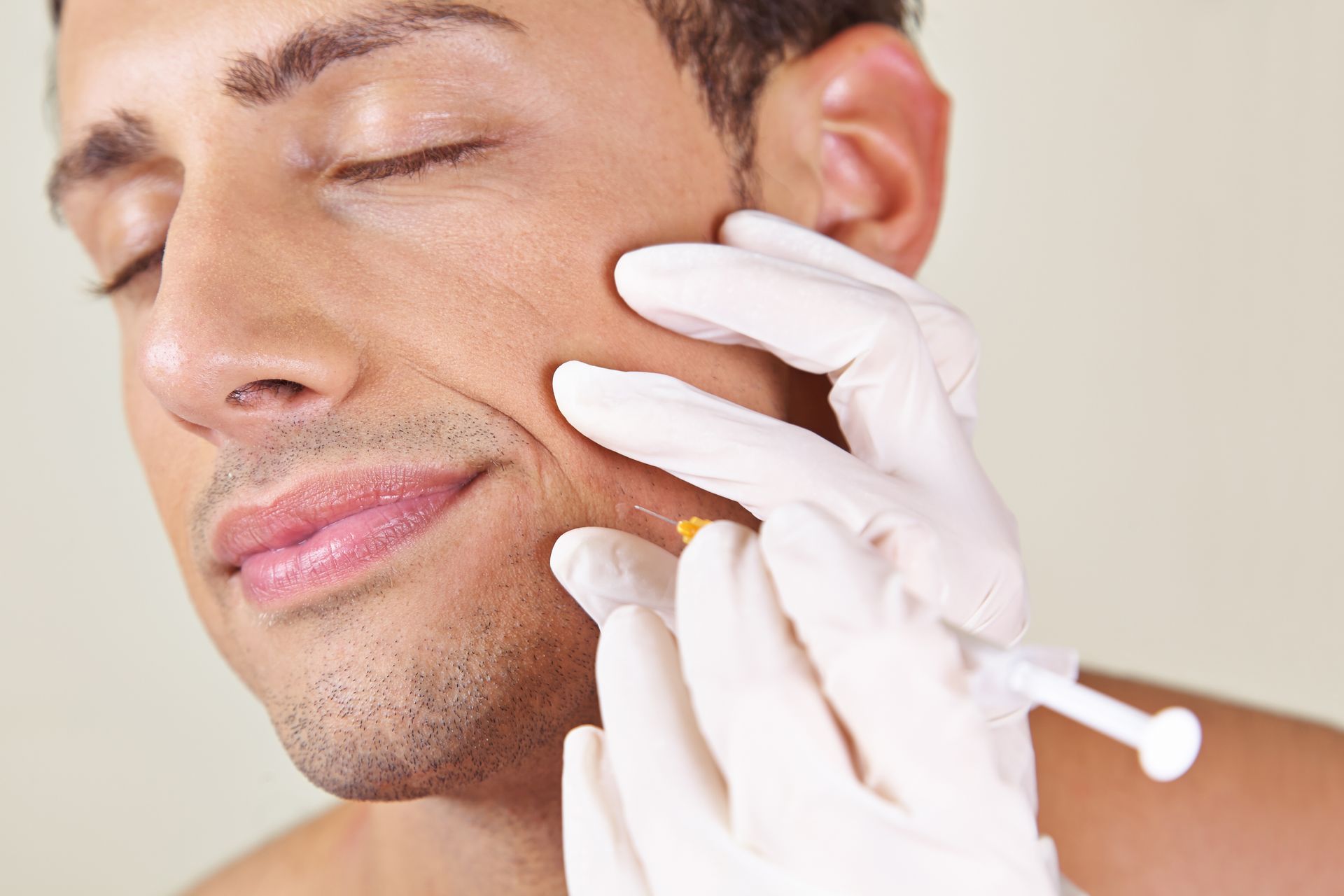 Man receiving facial injection with gloved hand.