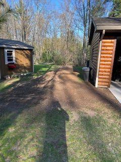 A dirt road leading to a house and a garage.
