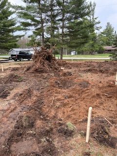A dirt field with a truck parked in the background and trees in the background.