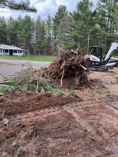 A pile of branches is sitting in the dirt next to a bulldozer.