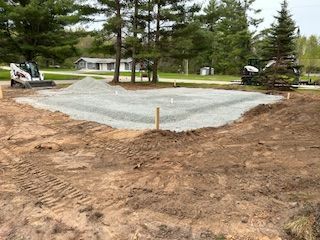 A large pile of gravel is sitting in the middle of a dirt field.