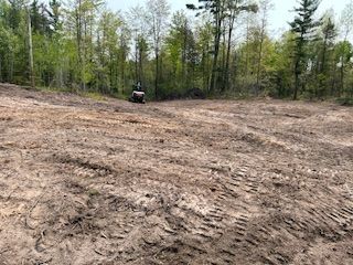 A person is riding an atv on a dirt road in the woods.