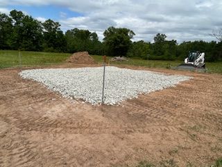A bulldozer is sitting on top of a pile of gravel in a field.