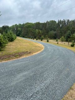 A curvy road going through a field with trees on both sides.